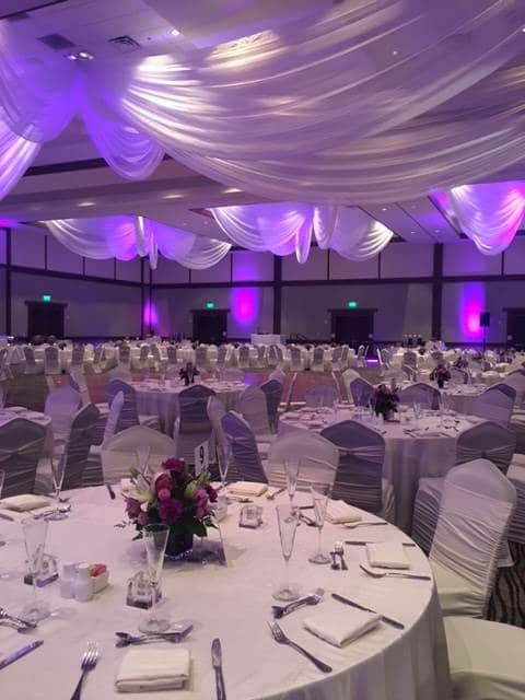 large reception area at Embassy Suites by Hilton with white curtains and purple uplights